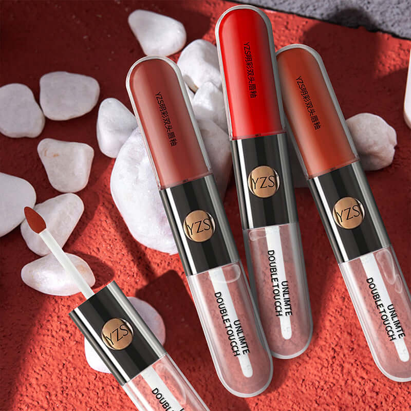Mirror Finish Lip Gloss tubes showcasing two shades and applicator on a textured surface with decorative stones.